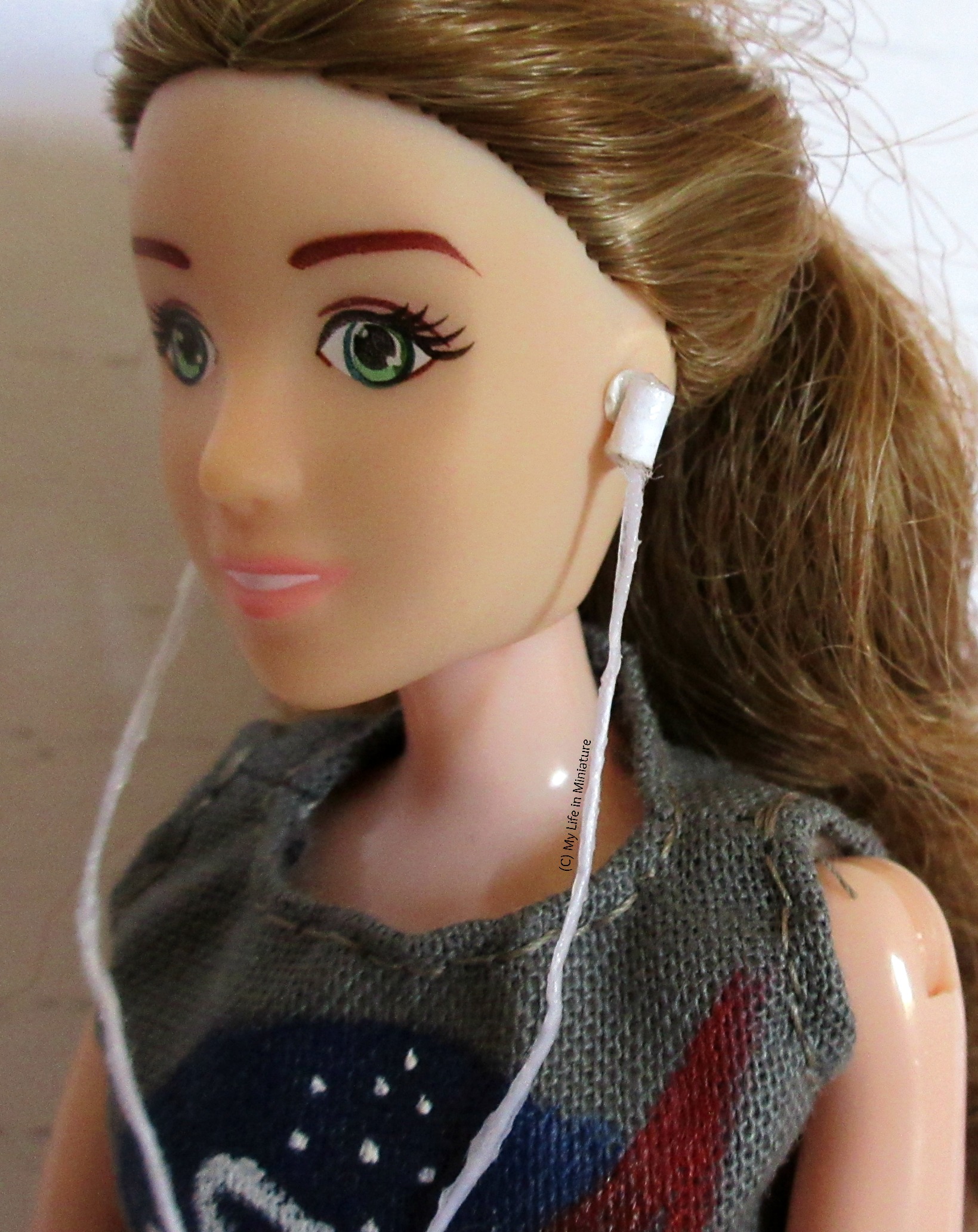 A close-up shot of one of the earbuds, as it sits blue-tacked onto Sarah's ear.