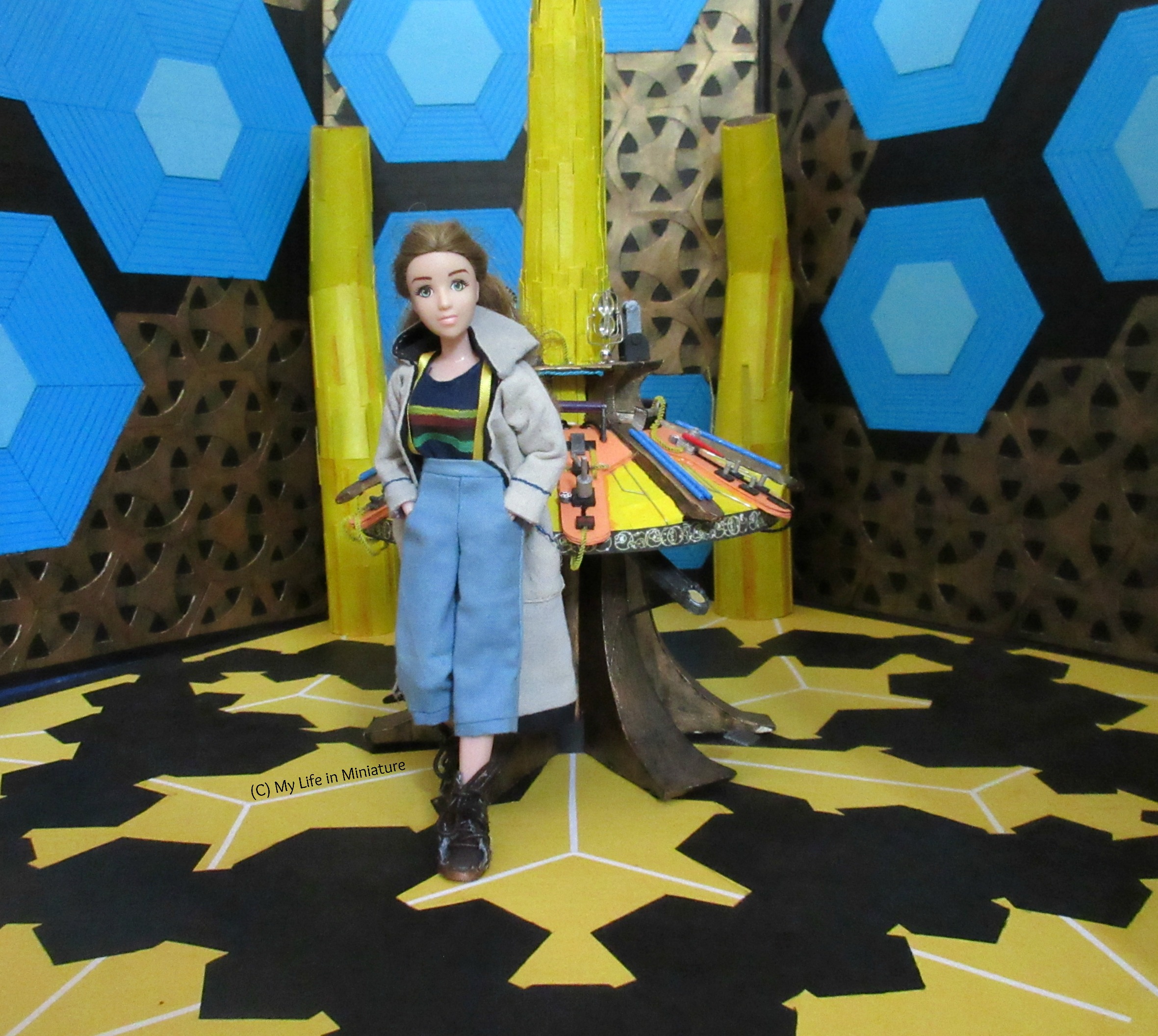 Shot is from the entryway to the TARDIS interior set. Sarah leans against the central console in Thirteenth Doctor cosplay, hands in pockets and looking at the camera.