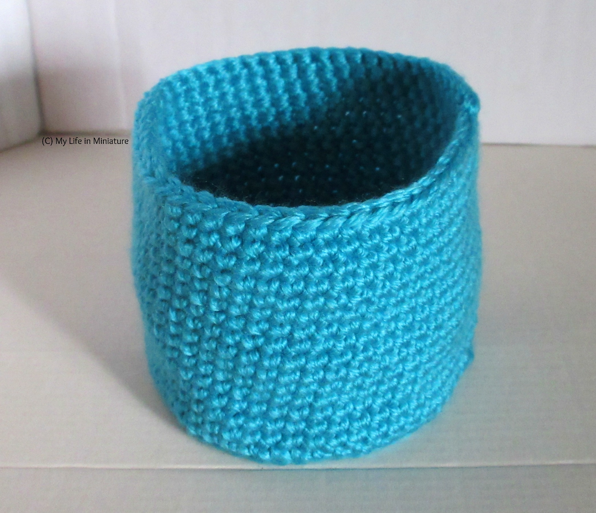 A blue crocheted nest sits against a white background.