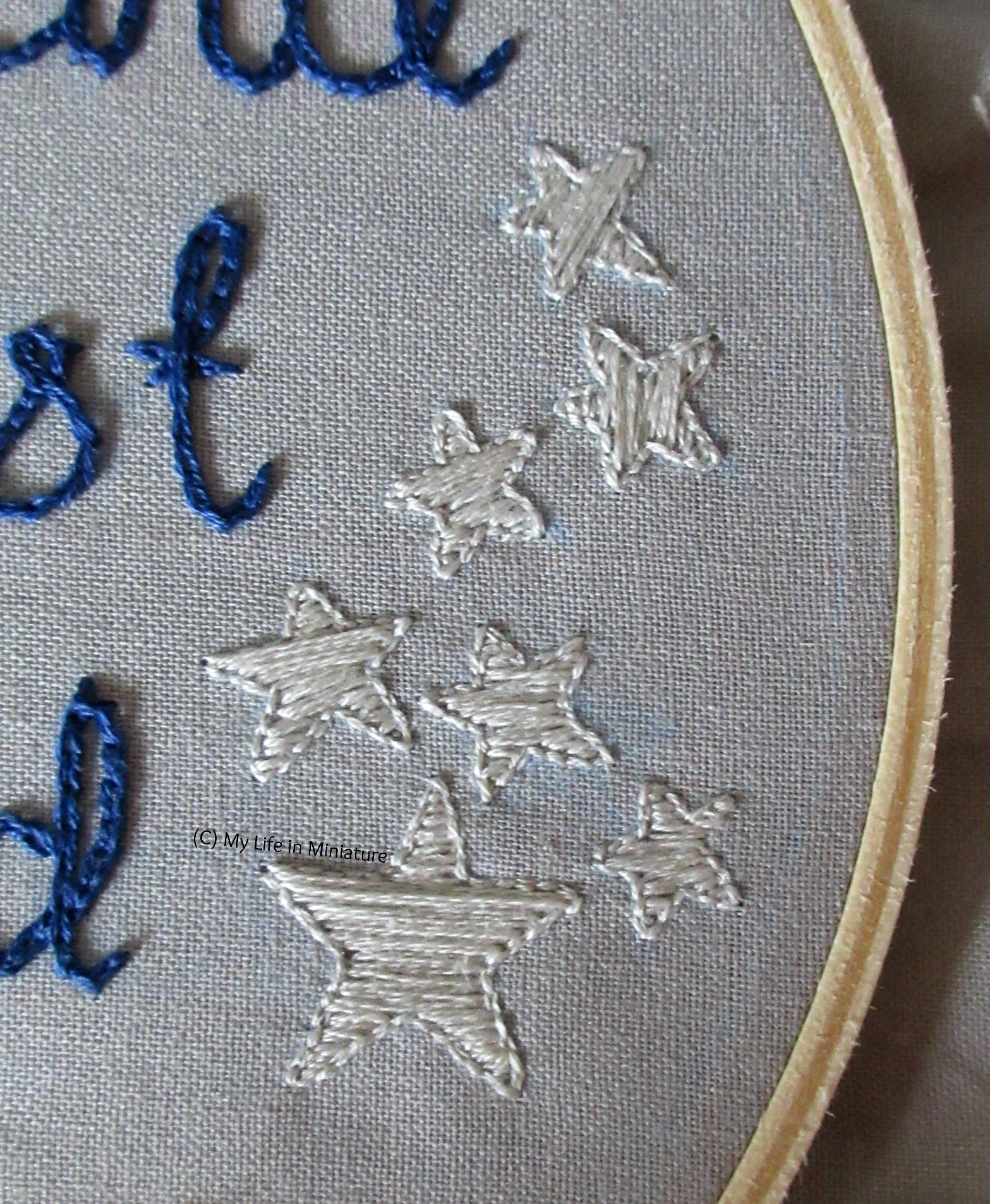 Close-up of the silver stars on the right of the hoop. They are filled in with satin stitch in silver. 