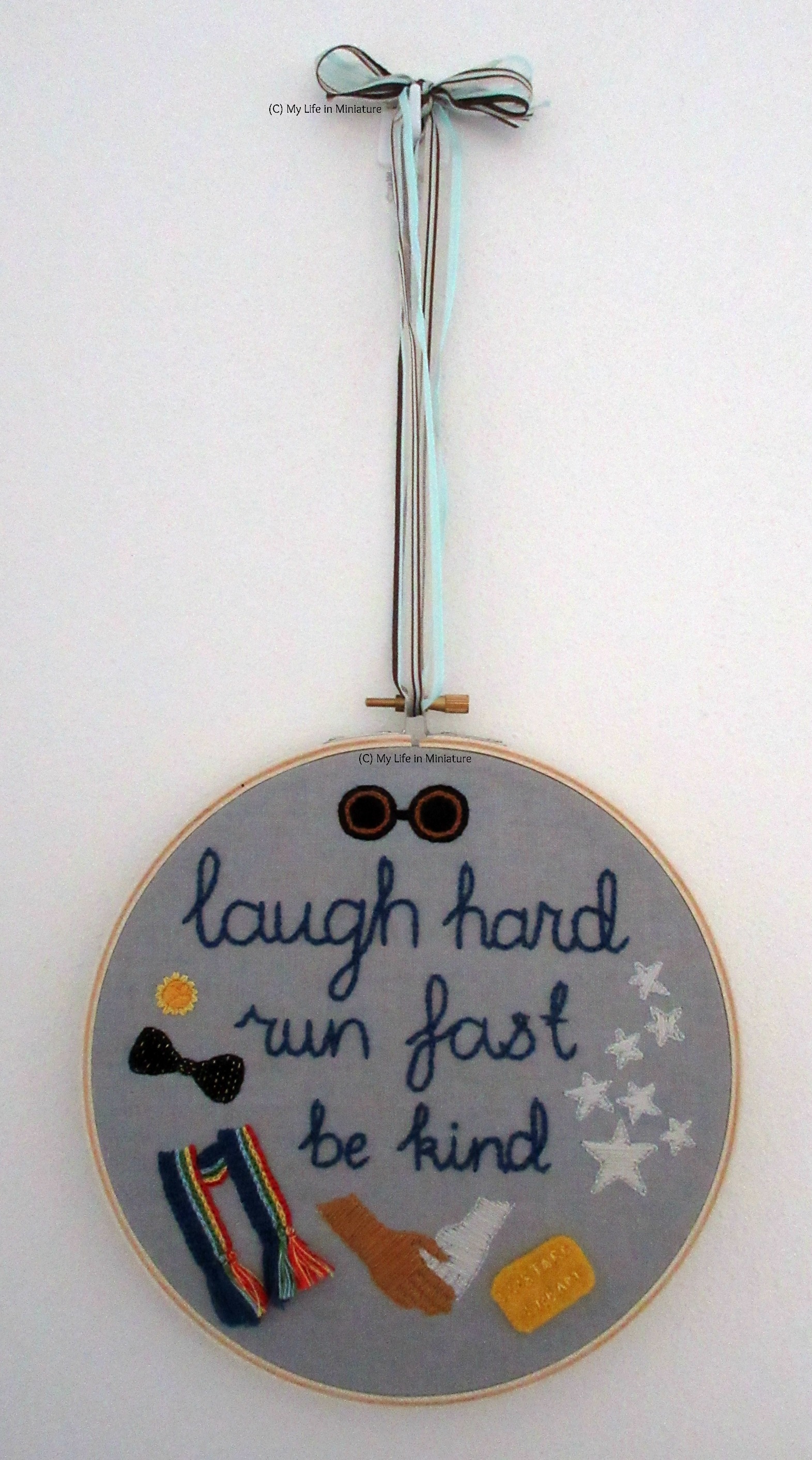 The hoop hangs from a ribbon on a white wall. 