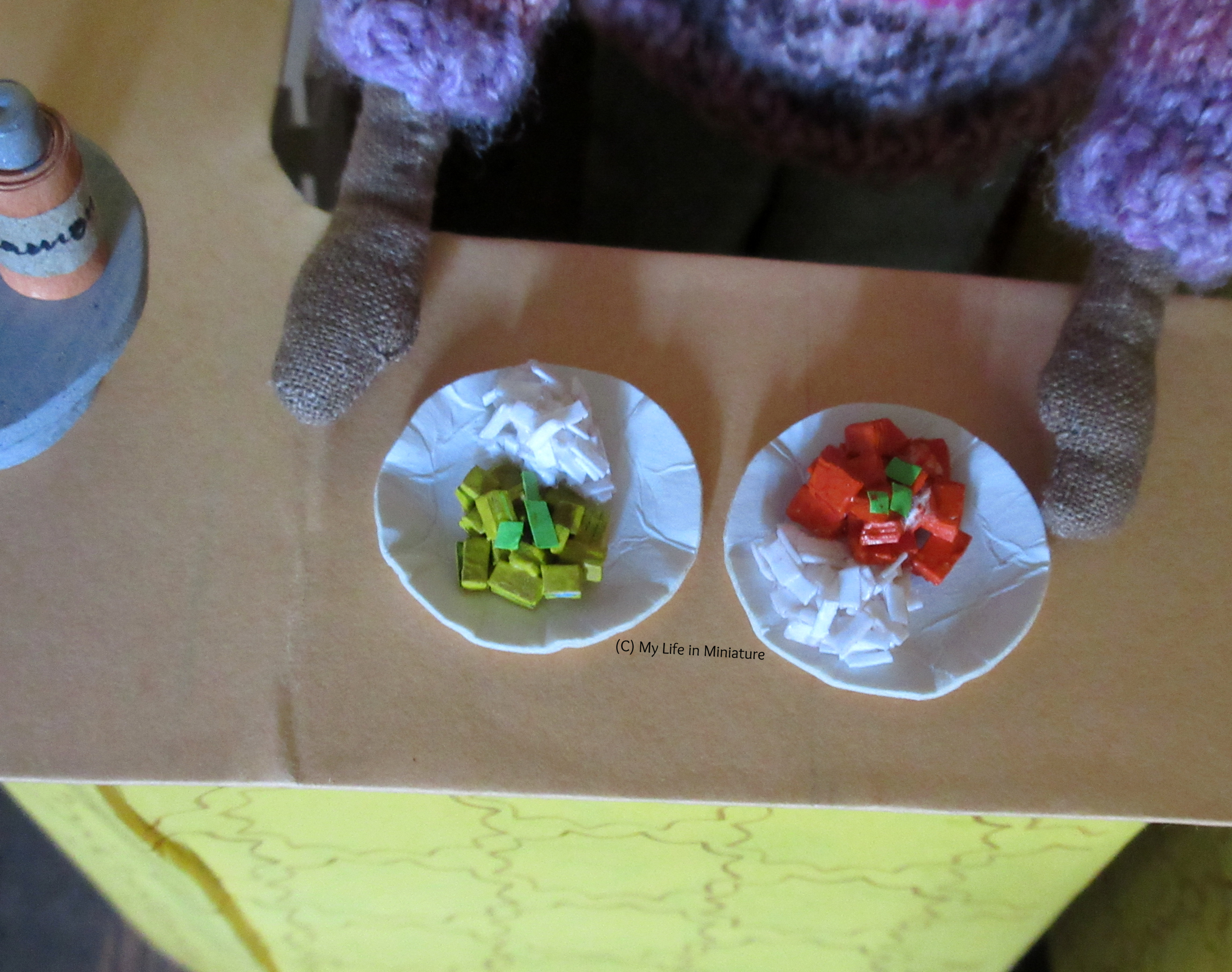 Petra is placing two plates of curry on the Tea at Yaz's curved counter. On the left is yellow beef curry, and on the right is butter chicken, both with rice. 