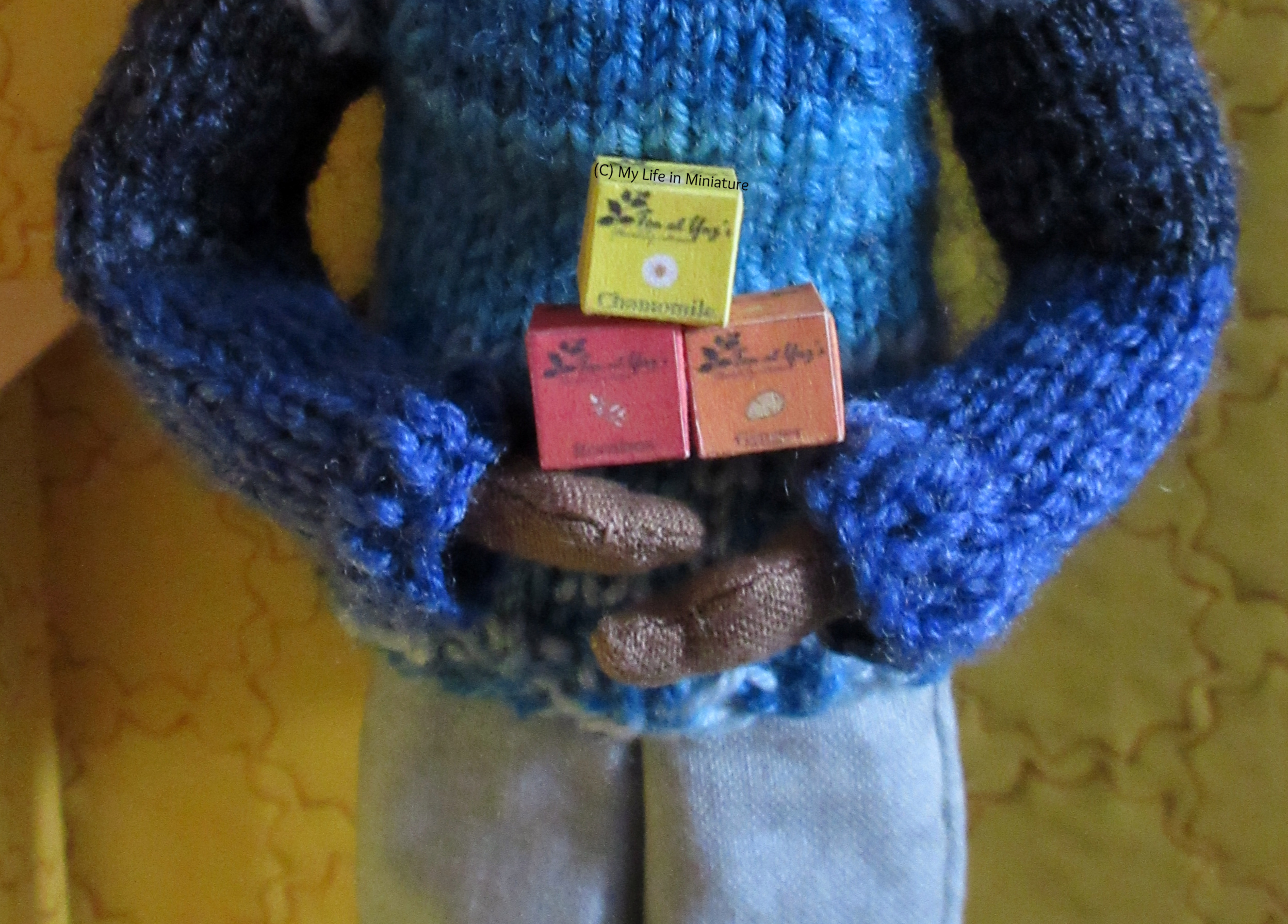 Petra holds three of the boxes in her hands, in front of her blue jumper. 