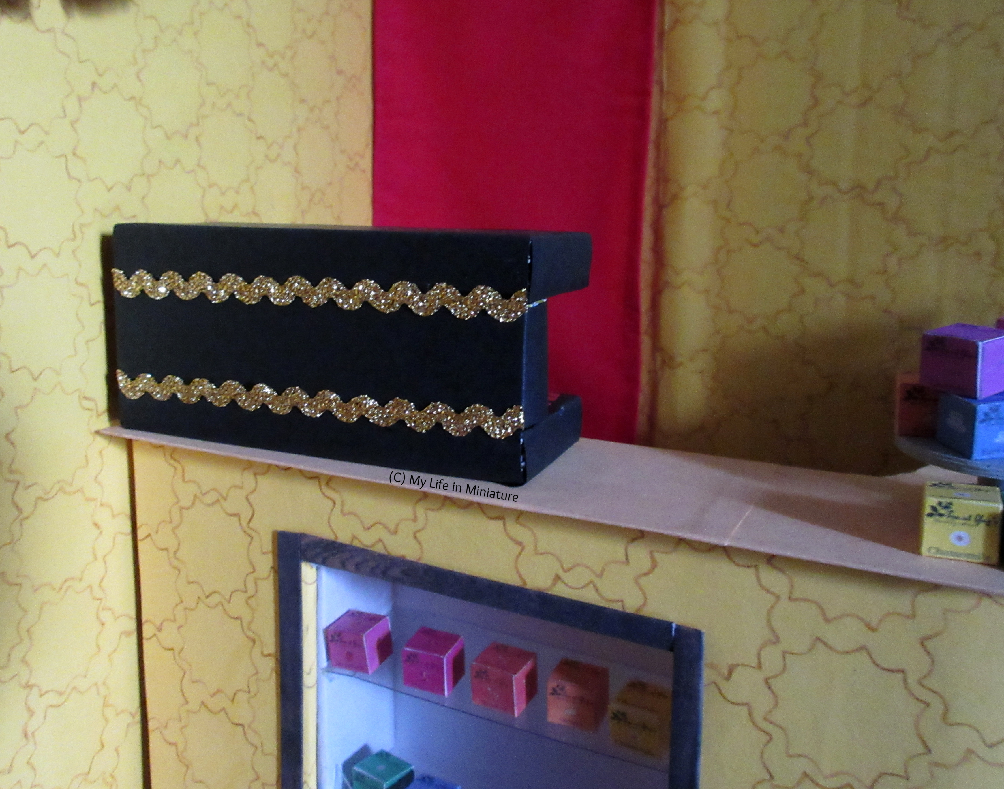 The coffee machine sits on the counter at Tea at Yaz's. The back of the machine is visible, and there are two lines of gold ric-rac on it.