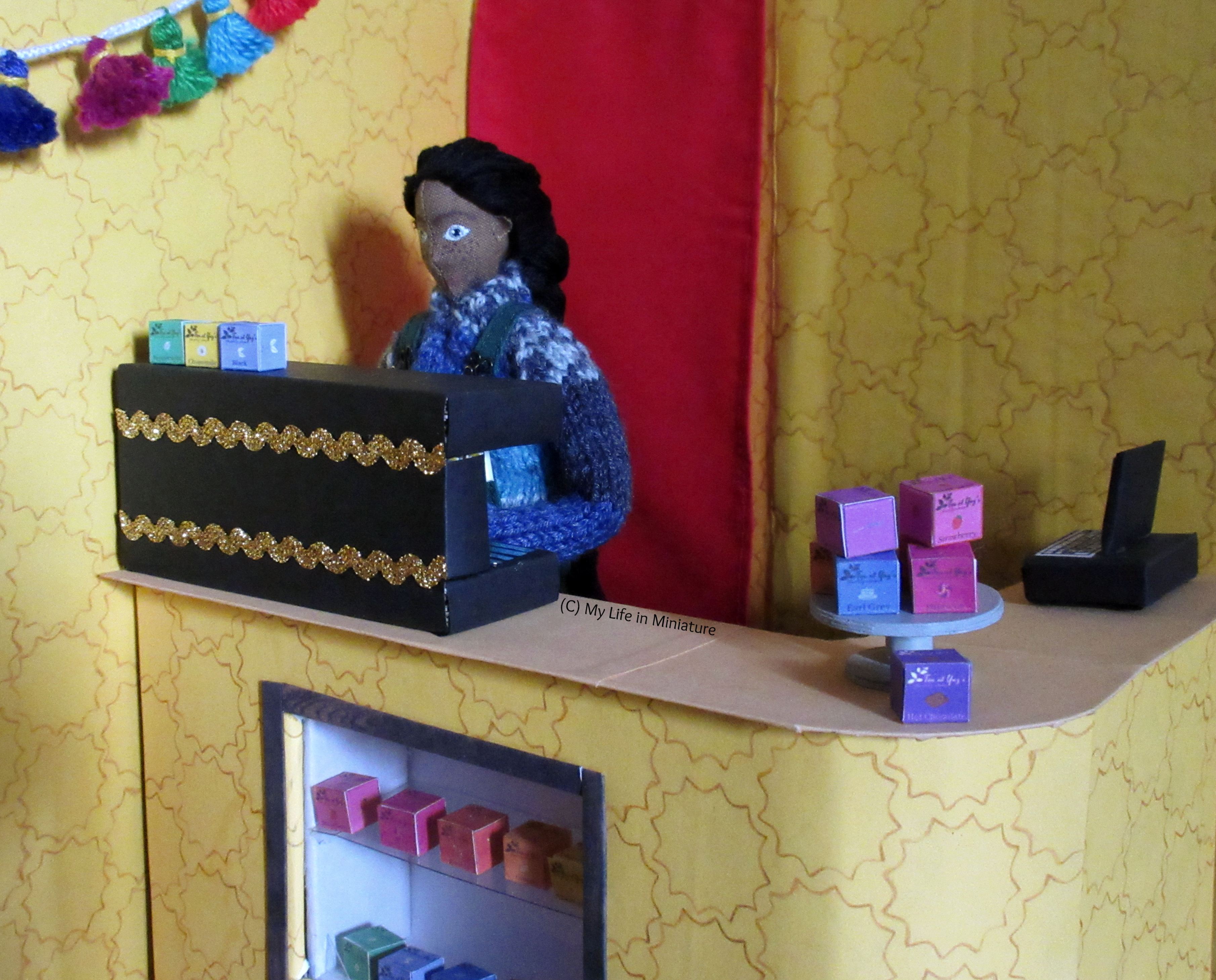 Petra stands behind the coffee machine, operating it, behind the counter at Tea at Yaz's.