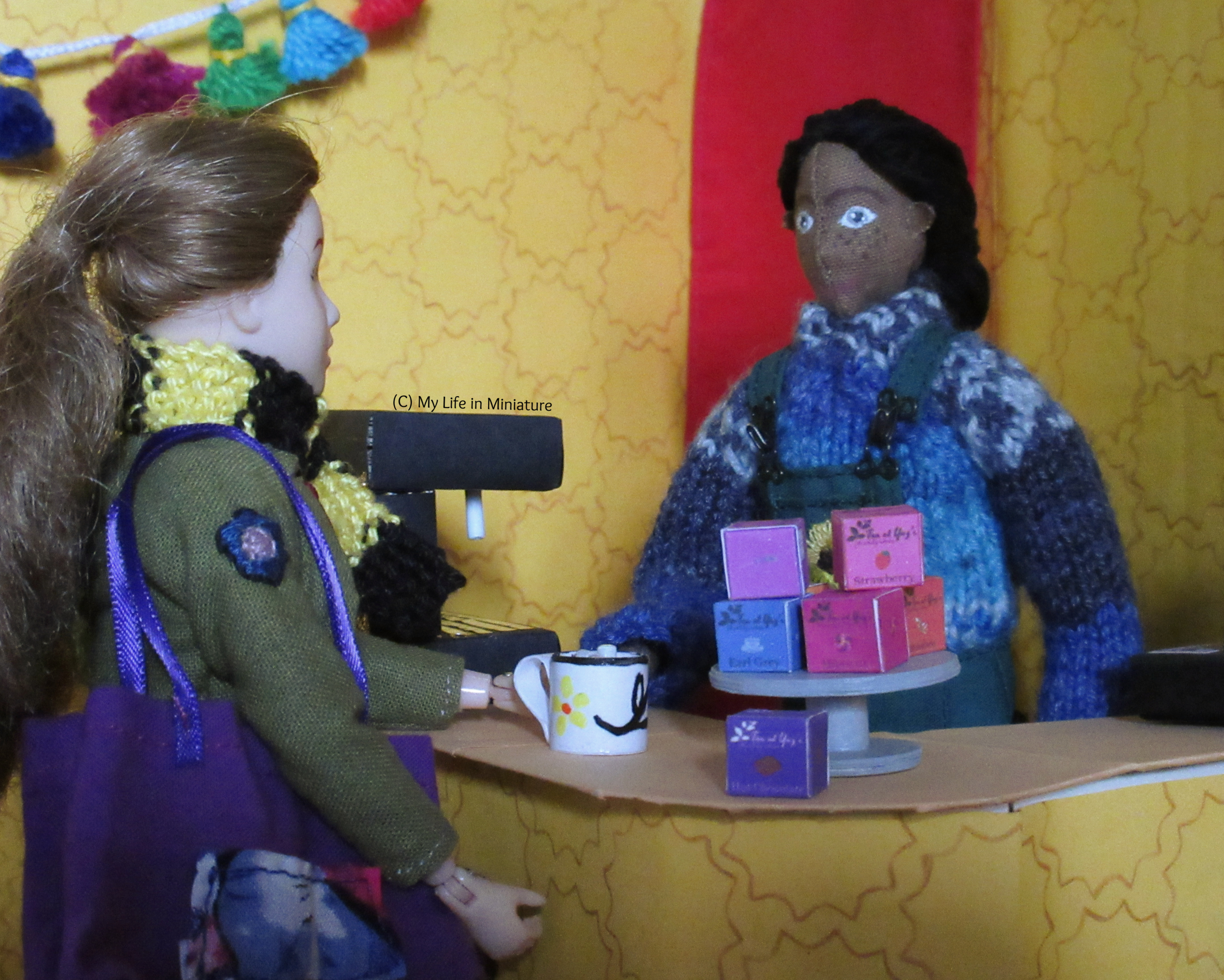 Petra slides a mug of hot chocolate across the Tea at Yaz's counter to Sarah. They both smile at each other.