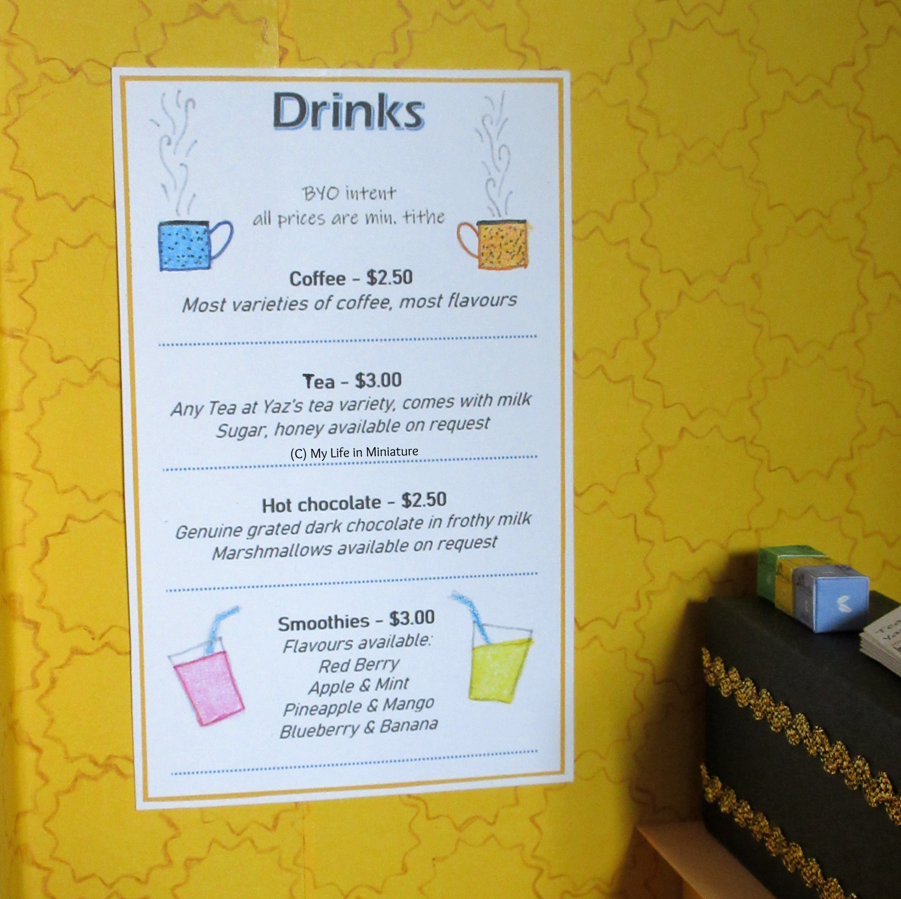 A drinks menu is on the wall of Tea at Yaz's, near the coffee machine. It lists the different drinks available, with their prices. 