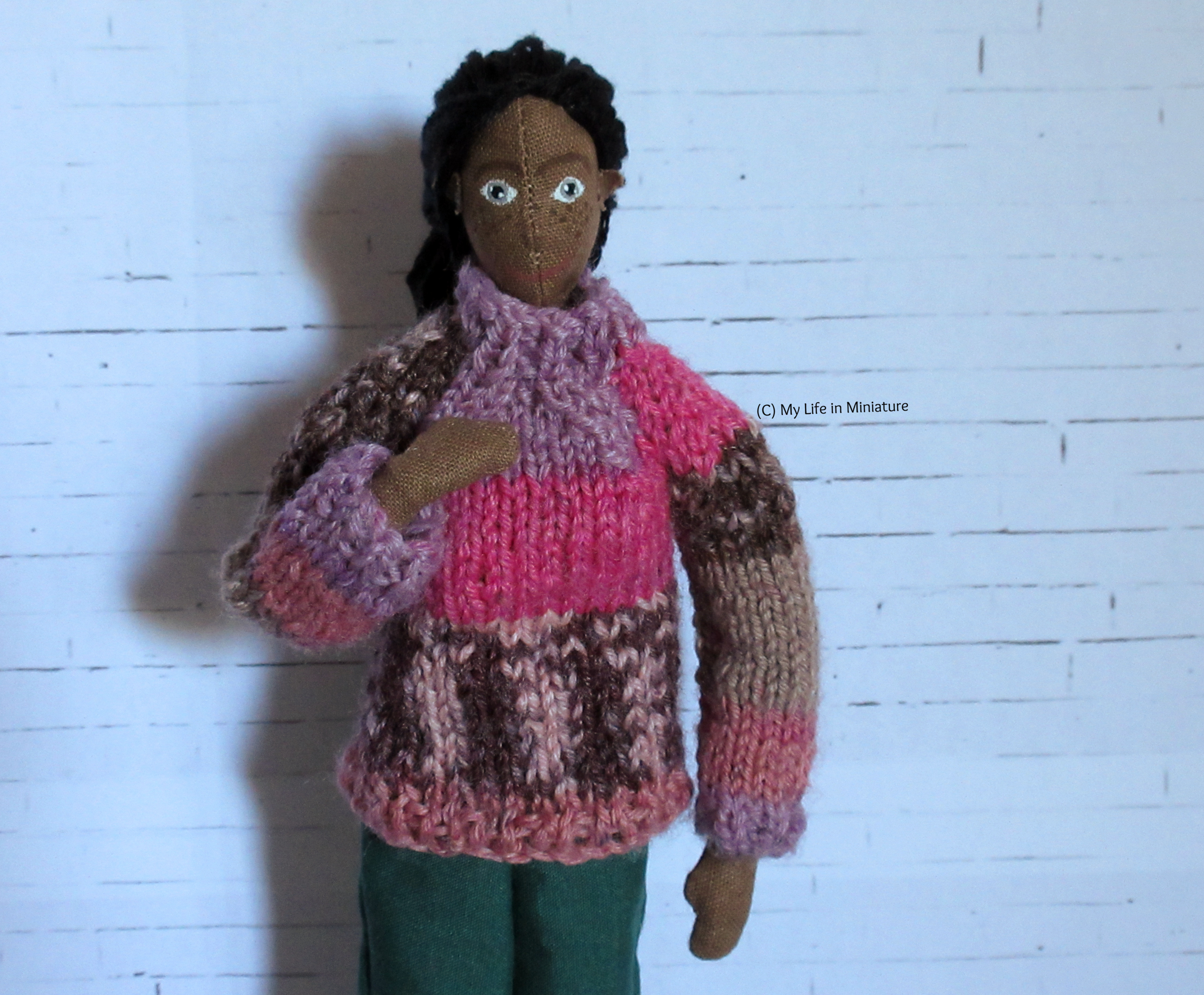 Petra wears the pink jumper, which now fits better at the neck, has longer sleeves, and a slimmer body. She looks at the camera.