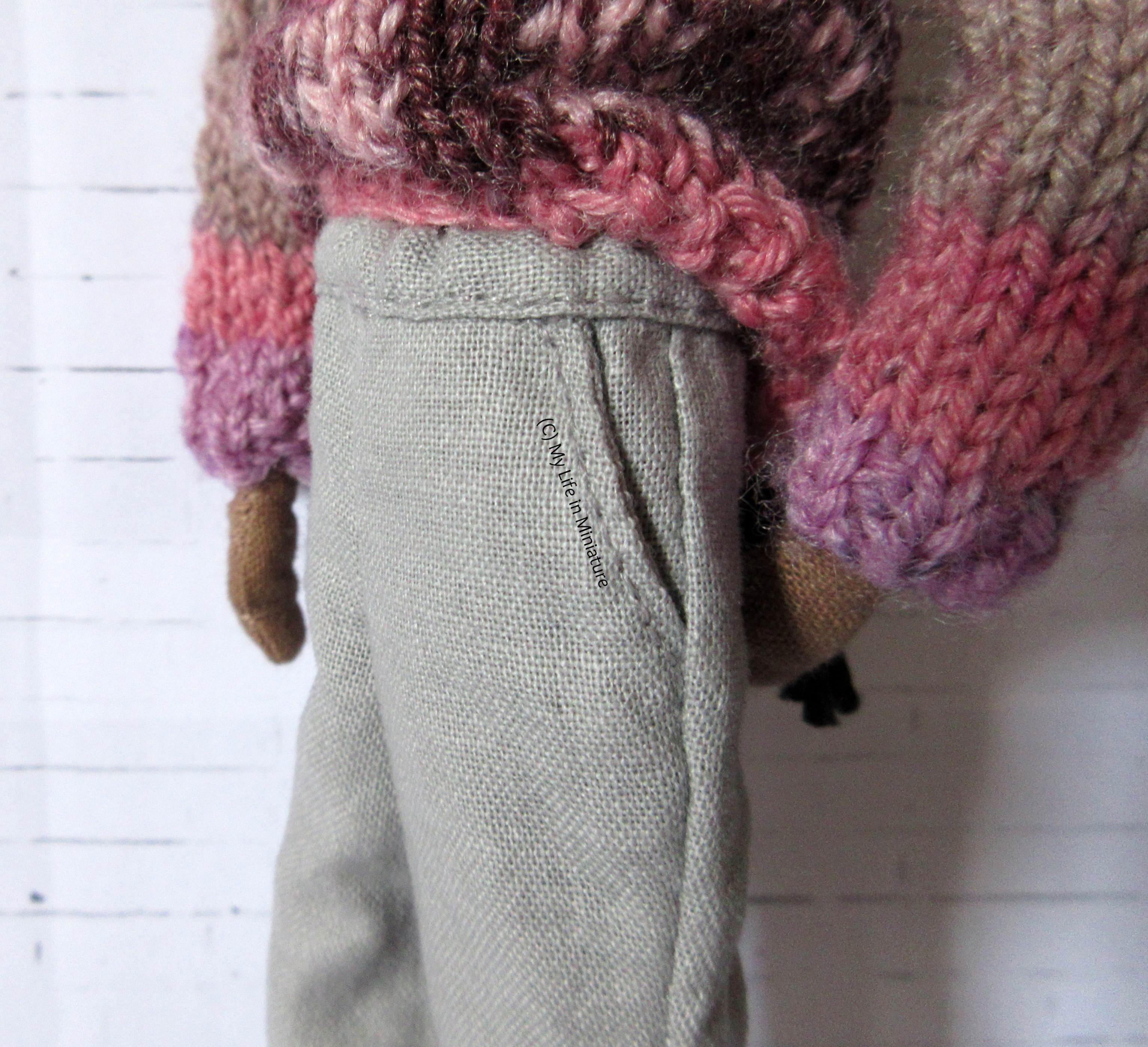 Close-up of the side of Petra's grey pants, showing the pocket opening in the side. Also visible is the waistband.