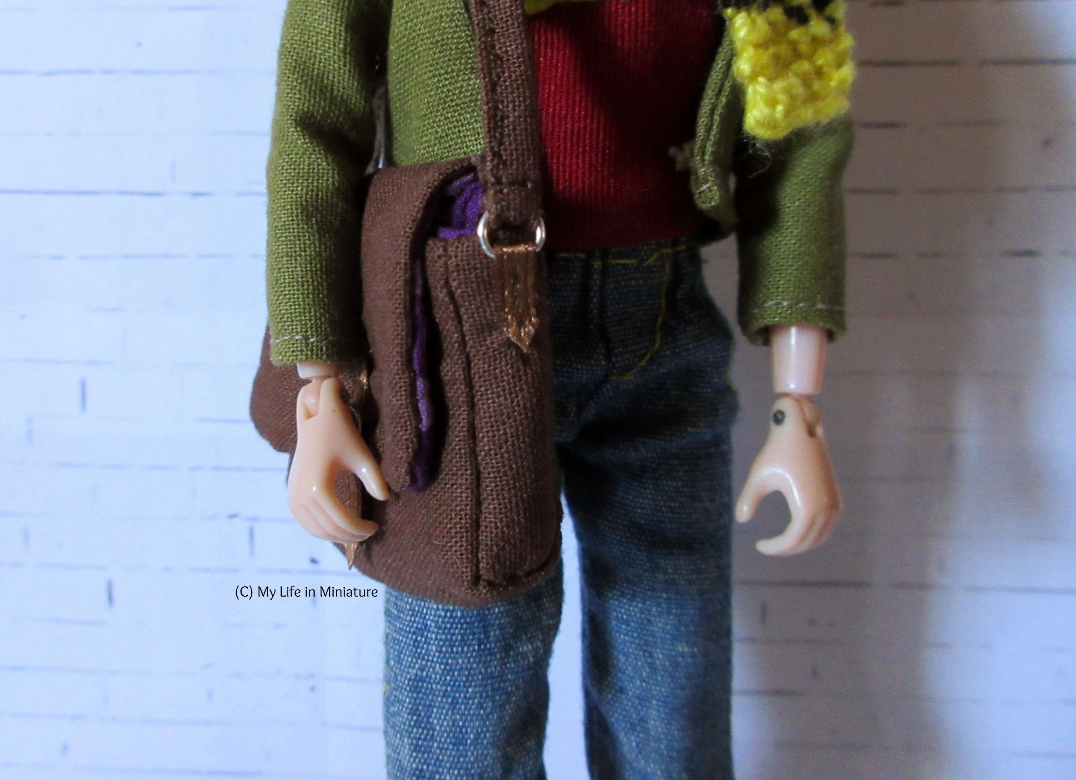 Close-up of the side of the bag, as it's over Sarah's shoulder. The silver D-rings are visible, sewn onto the side with a strip of brown ribbon. 