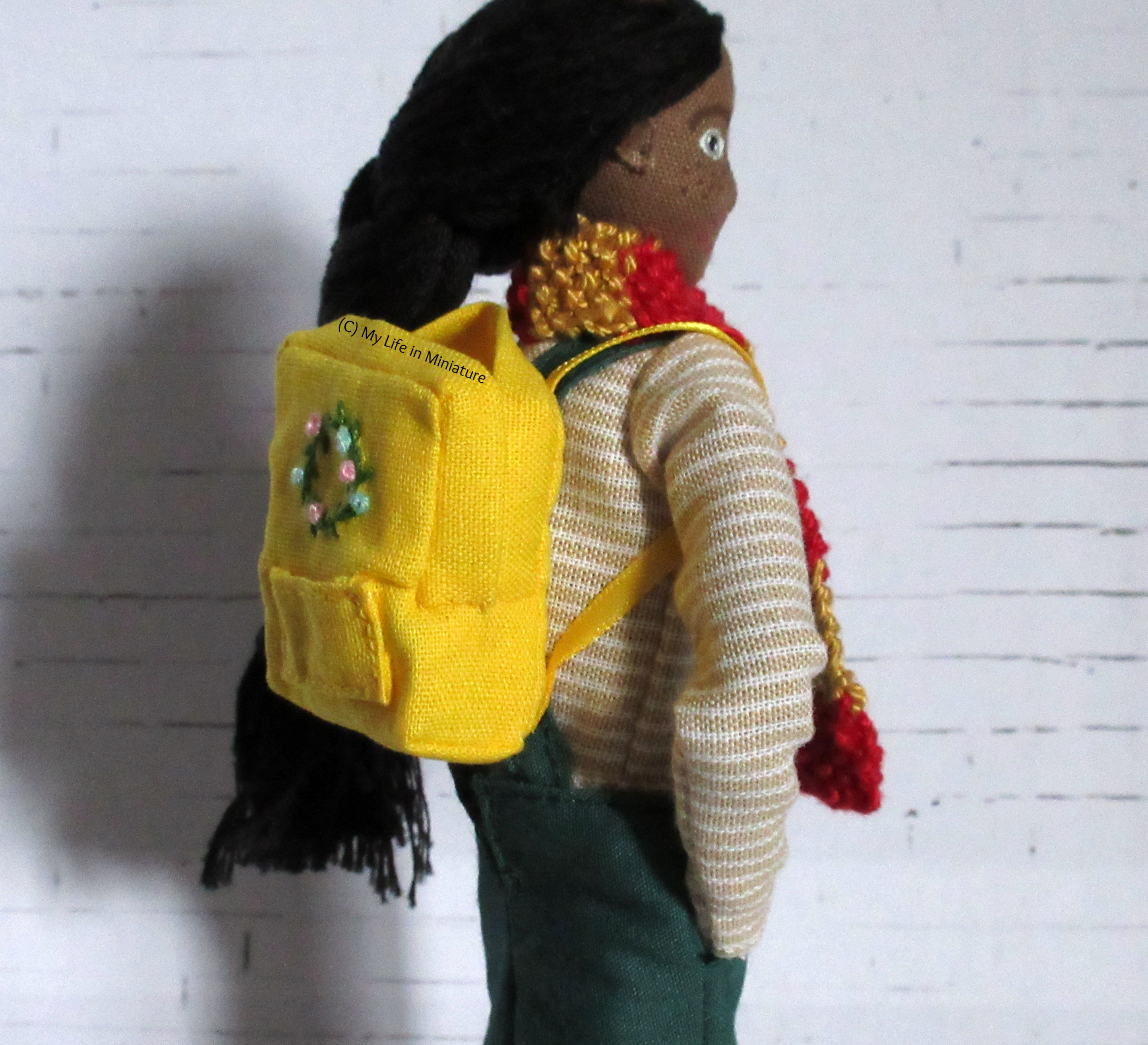 Side-on view of Petra wearing the backpack. The yellow ribbon straps are visible, as well as the side of the backpack.
