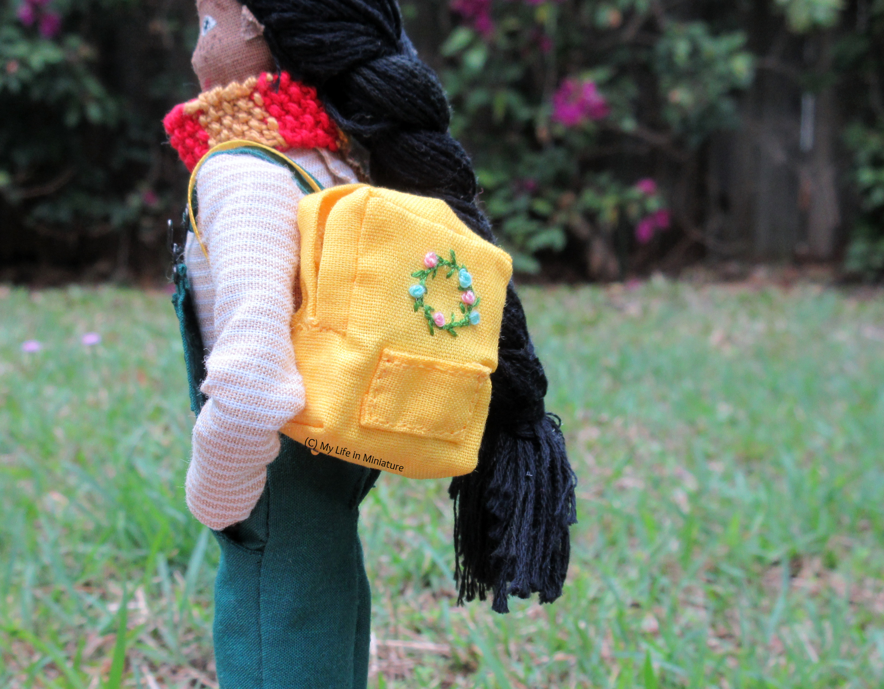 Petra stands outside, side-on to the camera. The backpack is over her closest shoulder. 