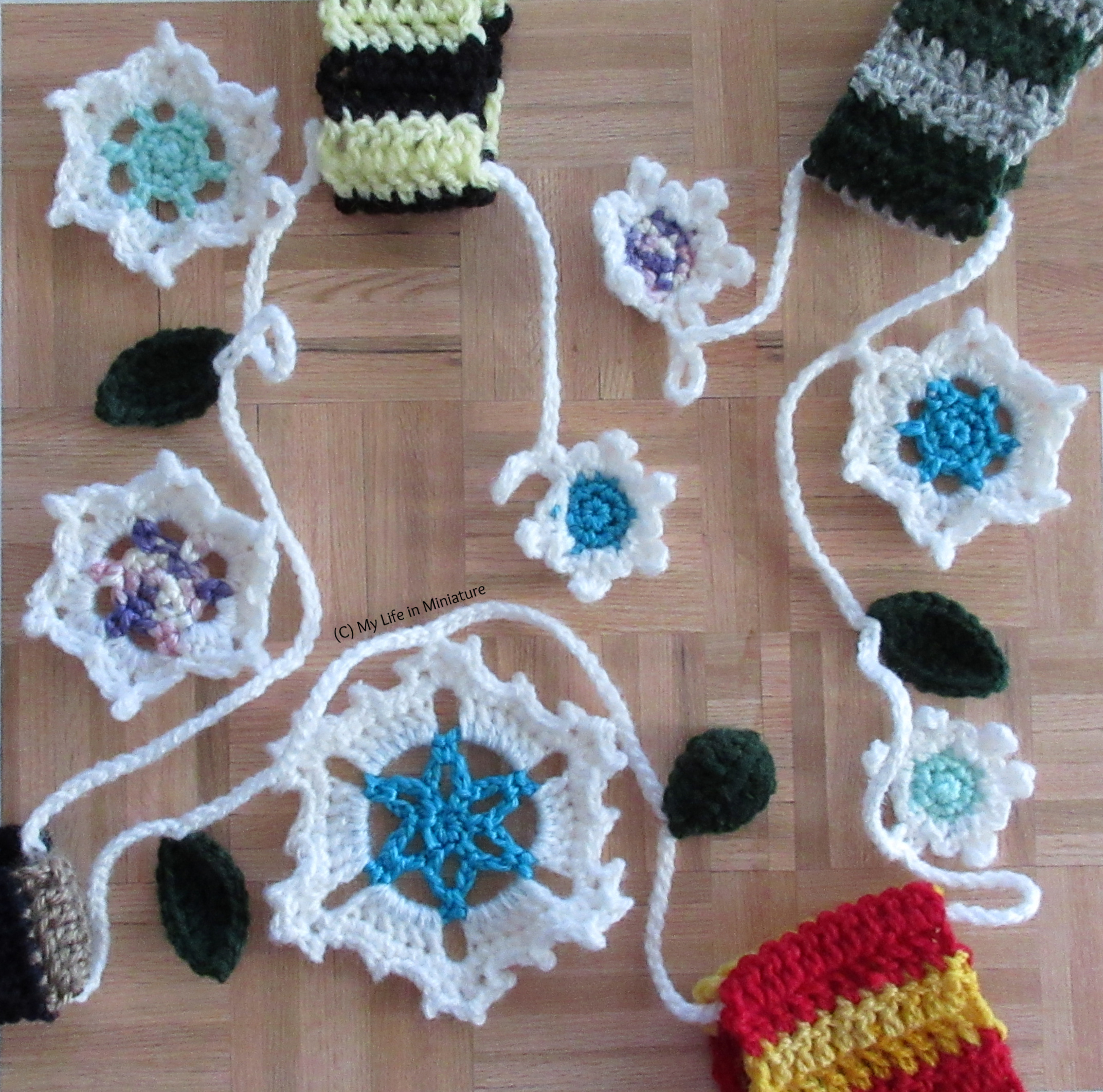 The wintery garland is arranged on a wood parquet background.