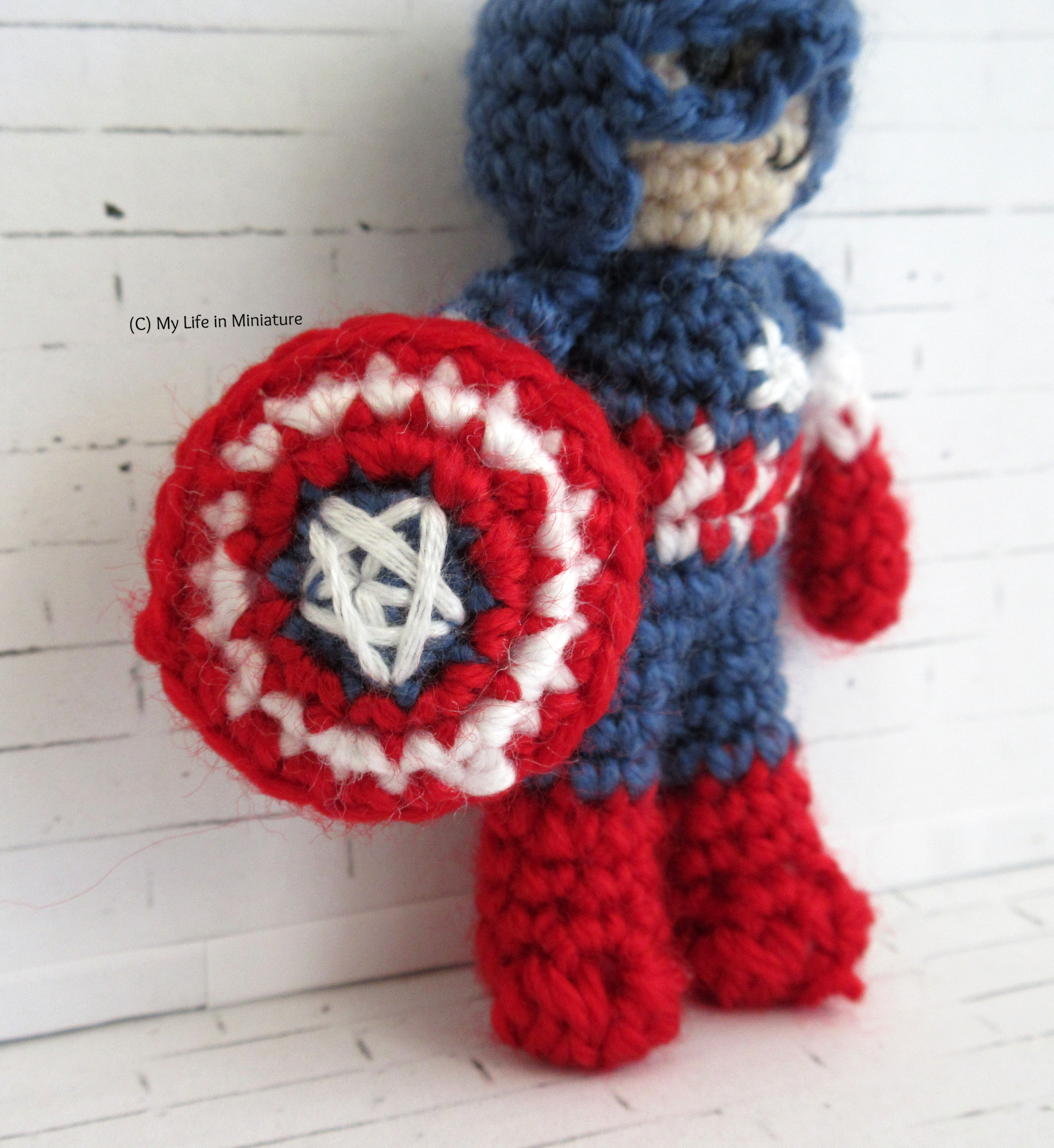 Close-up of the shield, which has a badly embroidered white star in the middle in a blue background. There are three rings of colour going out from the blue centre, which are red, white, and red. 