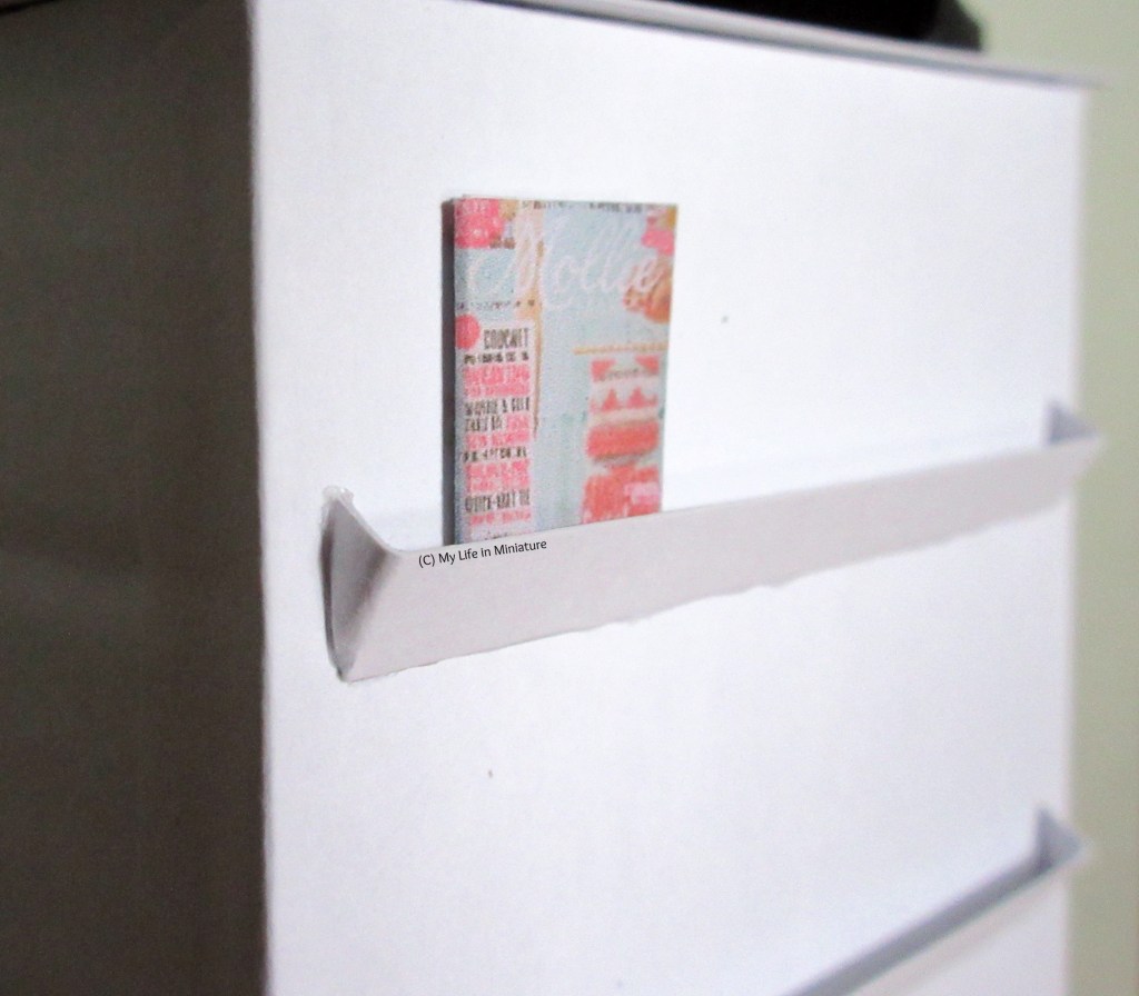 Close-up of the top magazine rack on the front of the counter. There is a craft magazine on the rack.