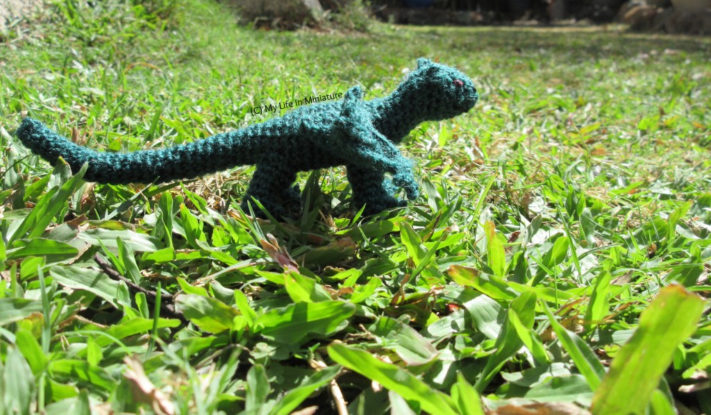 The dragon stands outside, under sunlight on grass. 