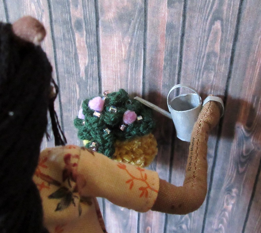 Over-the-shoulder shot of Petra watering one of the hanging baskets in Tea at Yaz's courtyard. 