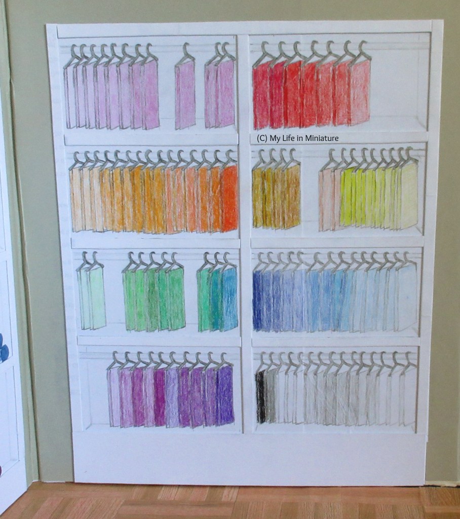 Full view of Needle & Thread's fat quarter shelves. The fabric is hanging from dark grey coat-hangers, with colours arranged in rainbow order from top left to bottom right. 