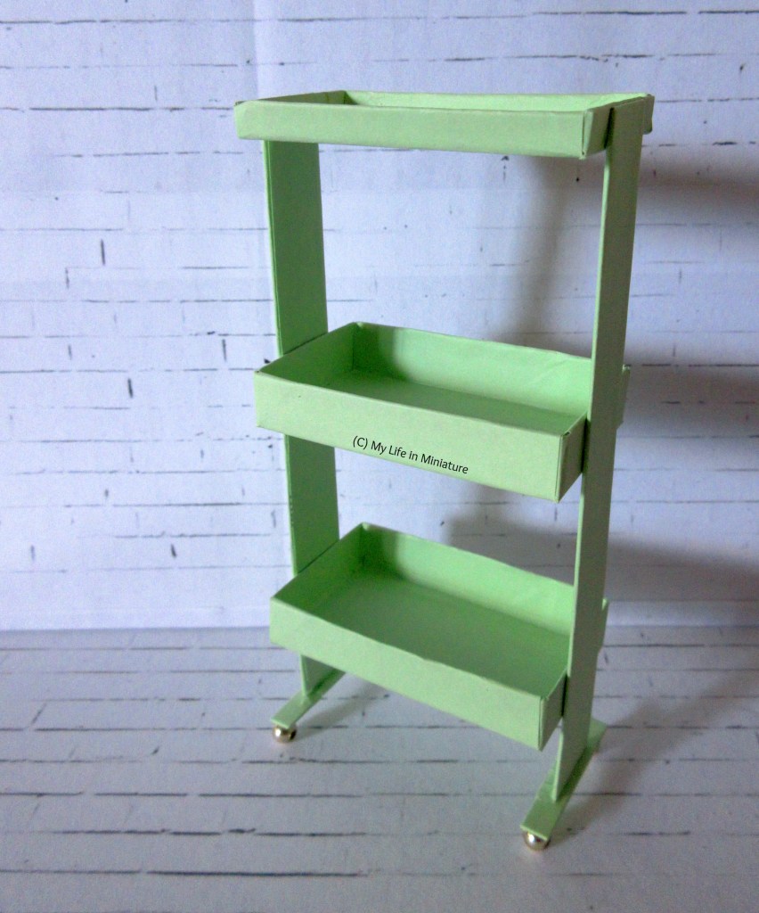 The green trolley sits in front of a white brick background.