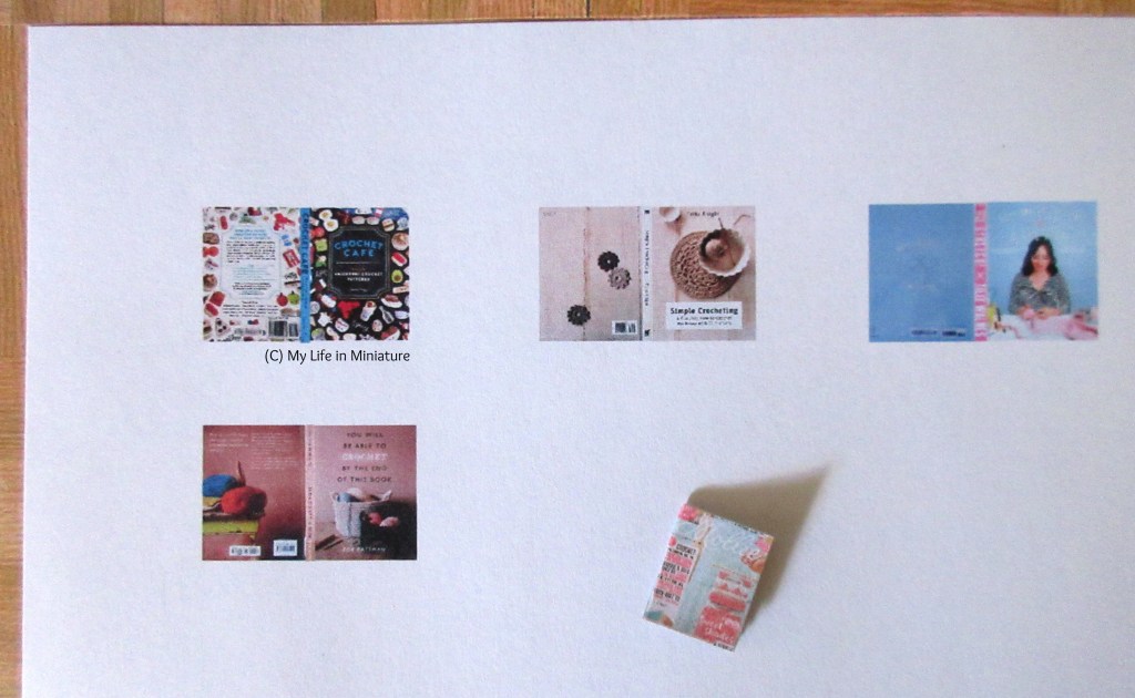 Overhead shot of the top-left of a piece of computer paper. On the paper is a miniature craft magazine, and printed onto the paper are four craft book covers.