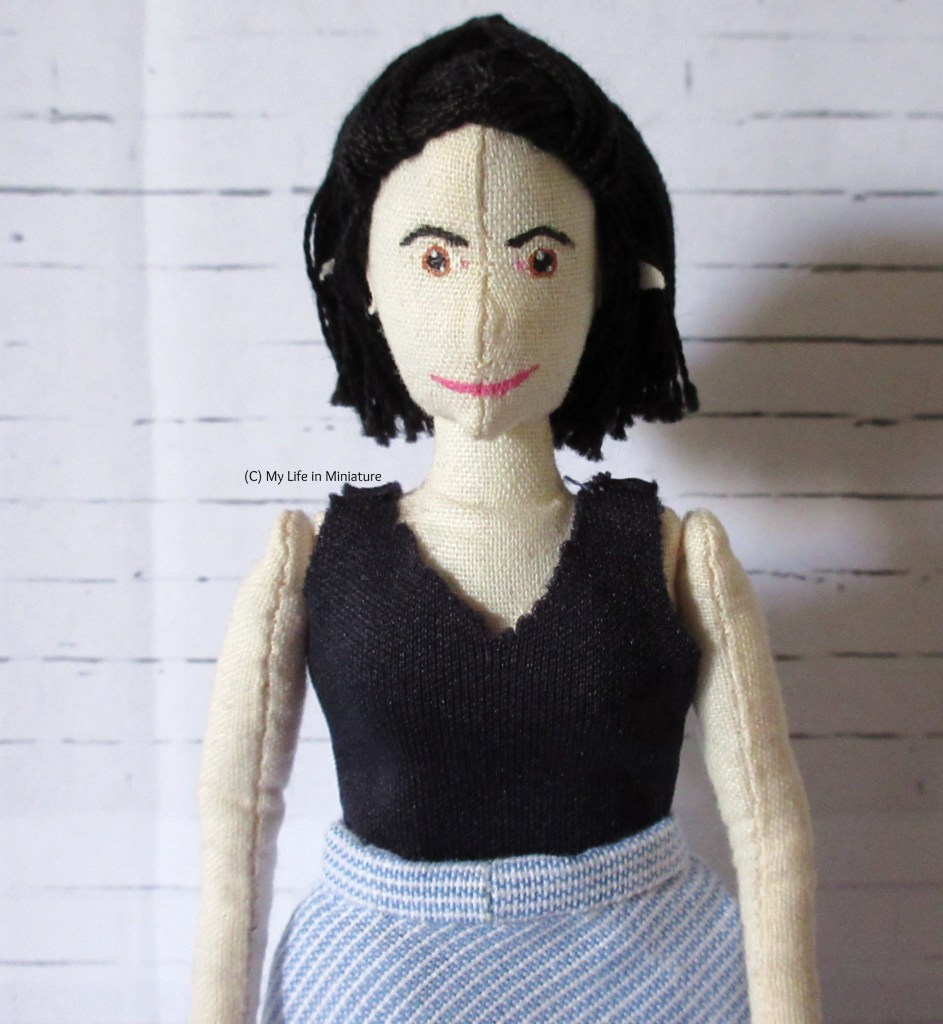 Tiffany wears the navy blue jersey top with her white-and-blue striped skirt. She is looking at the camera.