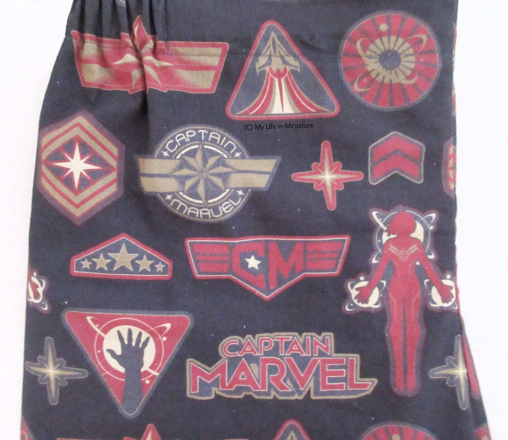 Close-up of the fabric. It has the movie logo and various symbols related to the MCU character, like her star and stripes, and a rocket ship taking off.