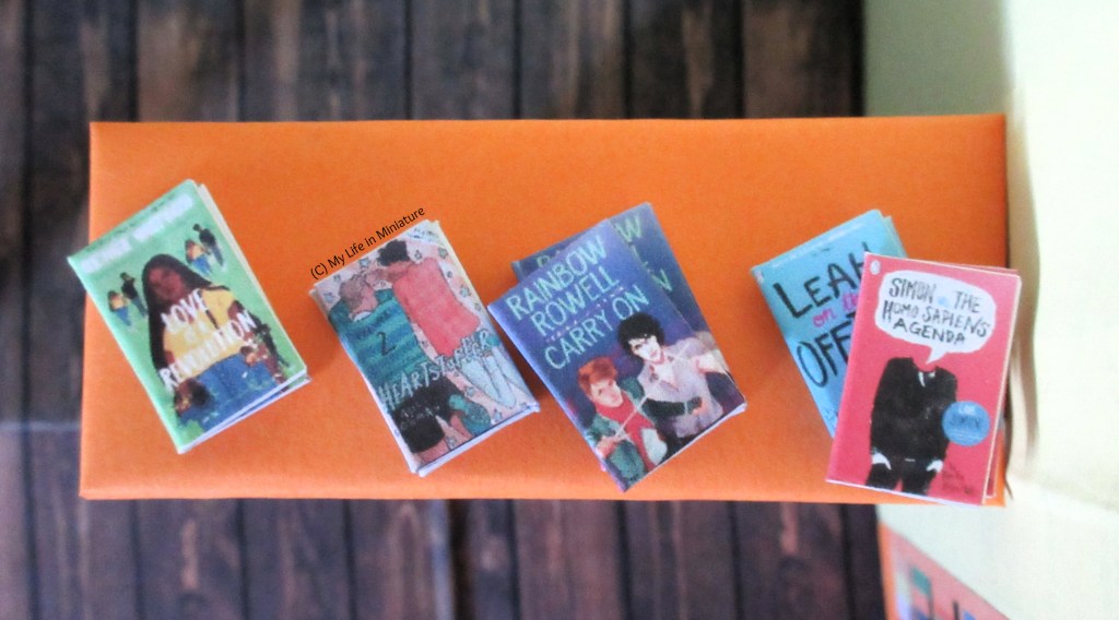 Birds-eye view of the counter-top. On it are five books, in a row. The two on the right are stacked on each other. 