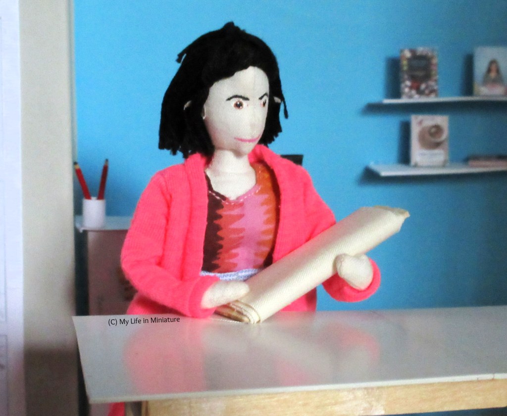 Tiffany stands at a fabric table in Needle & Thread. She holds a bolt of plain cream cotton fabric. 