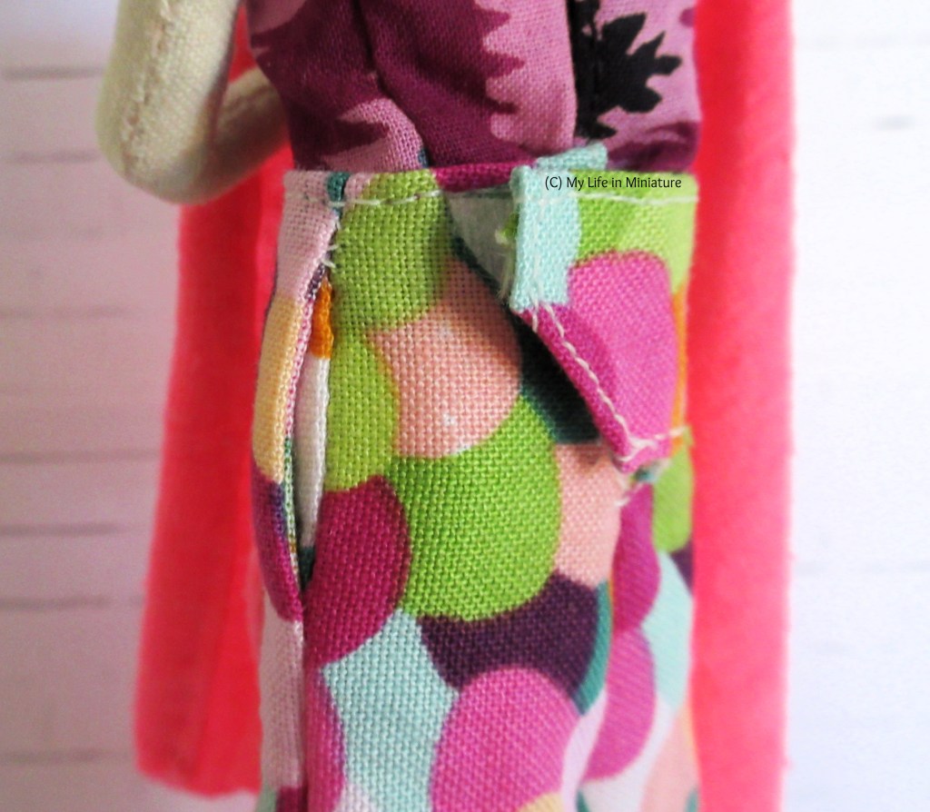 Close-up of the side of the multi-coloured pants, with the waistband, a pocket, and an angled flap at the back visible. 