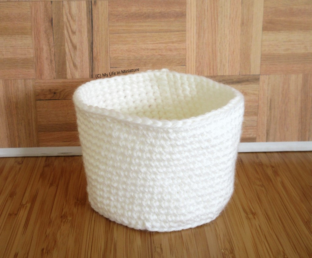 The completed white crocheted birds' nest sits against a wood background.