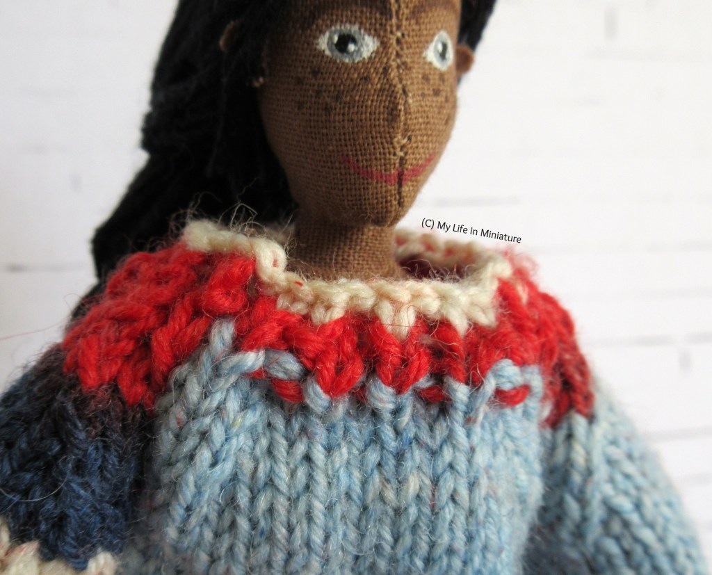 Close-up of the neckline of Petra's multi-coloured jumper. It is red and white knit ribbing, and sits just below her neck. 