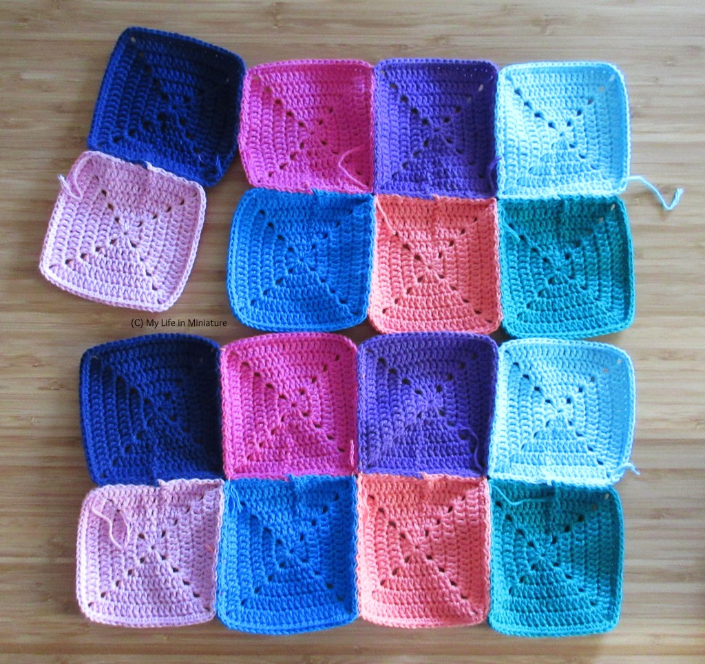 Two rectangles of crocheted squares are flat on a wooden background. Both rectangles are 2 by 4 squares; the bottom rectangle is completely sewn together, and the top one has two squares on the left partially connected to the rest. 