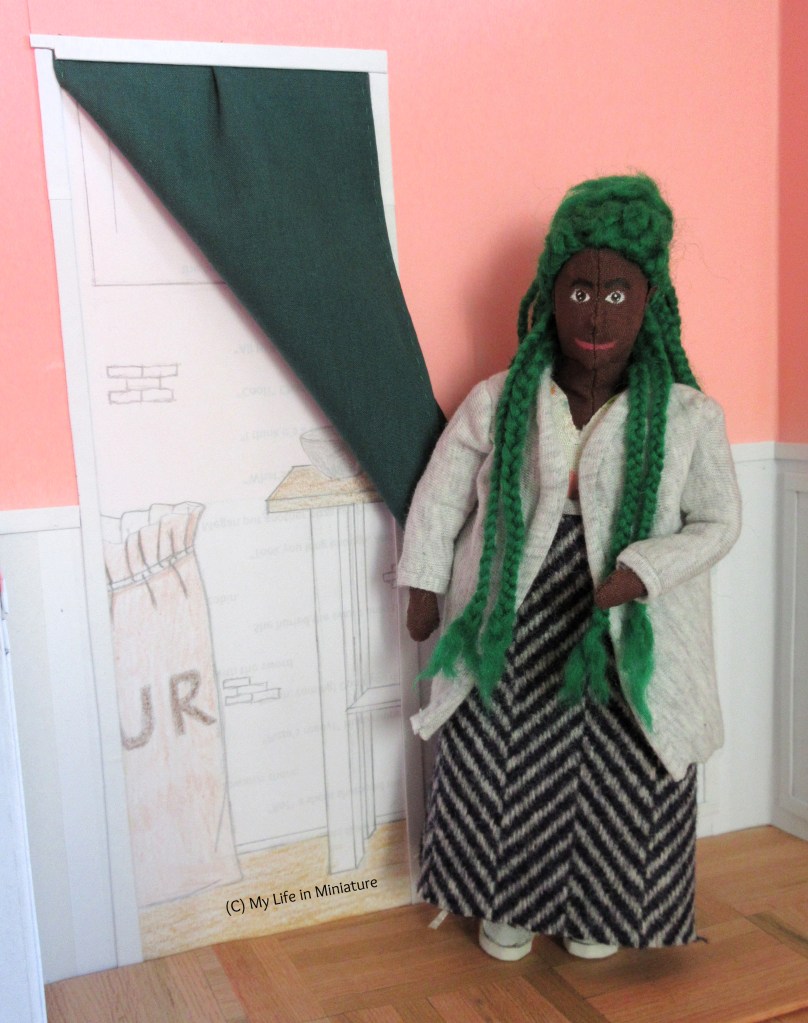 Hazel stands at the internal doorway inside Fierro's Bakery. She has swept the green curtain aside, and holds it open as she gestures towards the opening. She smiles at the camera. 