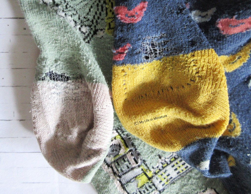 Close-up of two of the heels in the winter socks, with navy fabric covering the threadbare areas from the back. The left-hand sock is pale green with a pale beige heel, and the right sock is navy with a yellow heel.