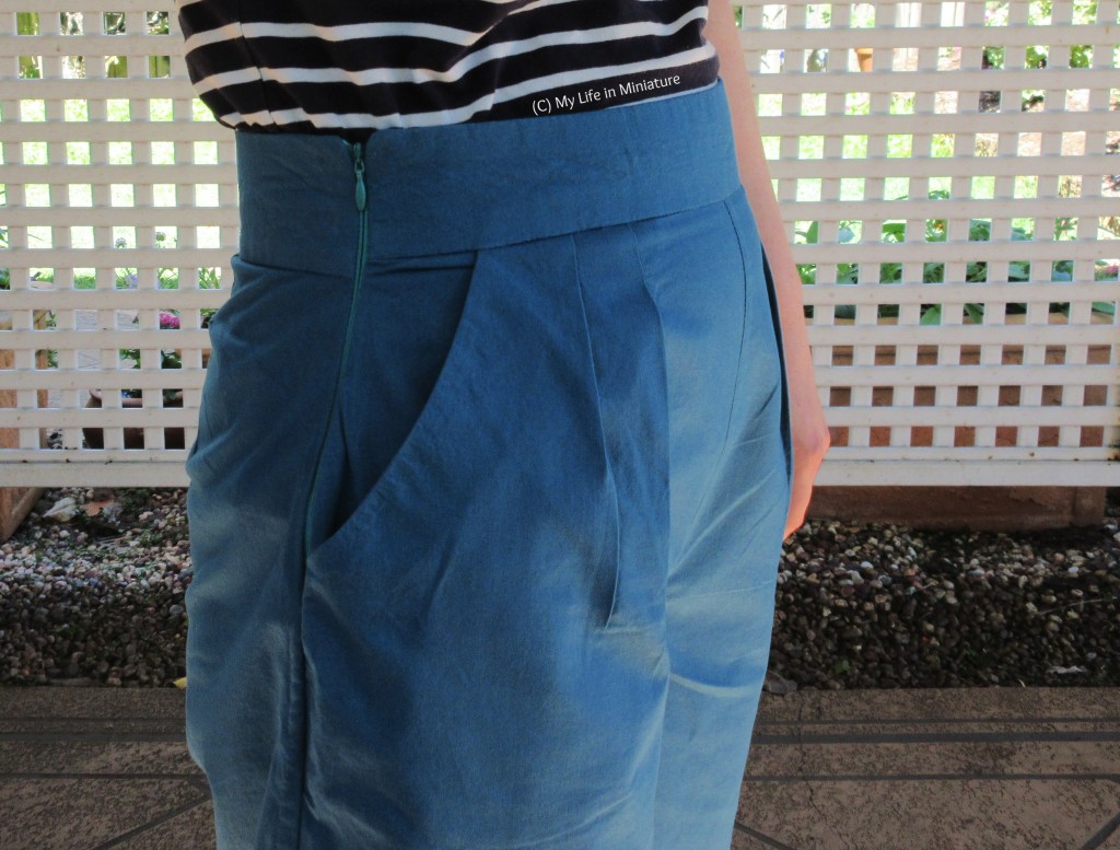 Close-up of the sea-blue-green pants' right side, allowing a good view of the invisible zip closure and one of the front pockets. 