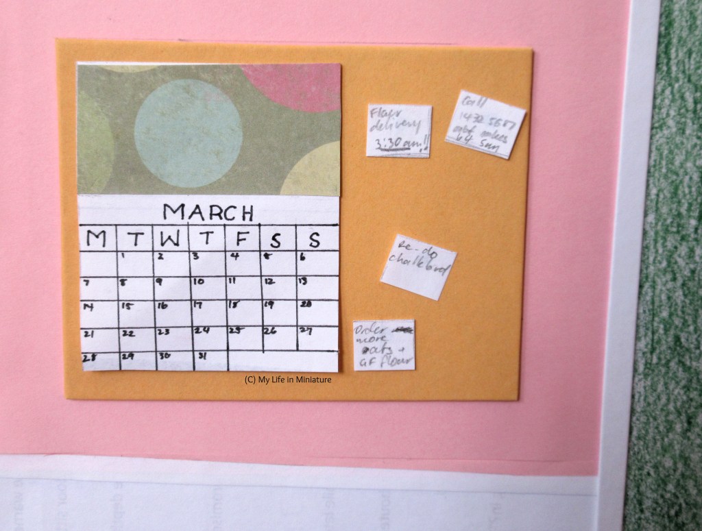 Close-up of the orange noticeboard, which is next to the doorway to Fierro's back room. The calendar displays March 2022, and there are four notes pinned to the board beside the calendar. They mention things like deliveries, jobs that need doing, and numbers to call back about orders. 