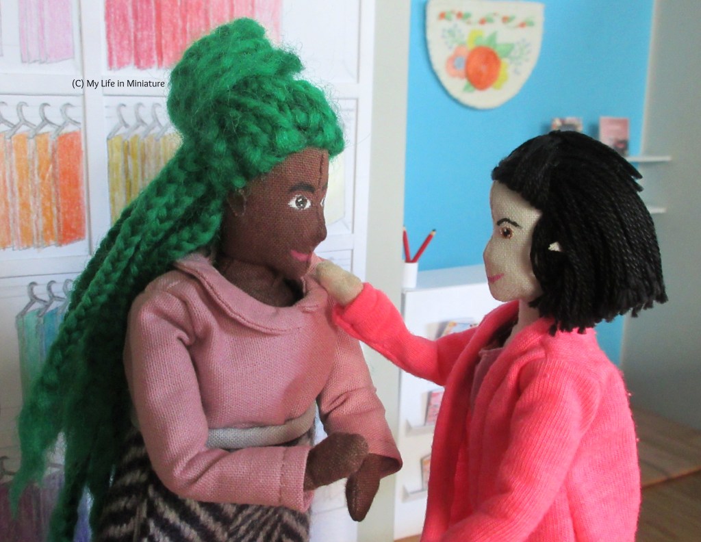 Tiffany and Hazel stand in Needle & Thread. Tiffany is fiddling with the collar corner that's sticking up, and Hazel has a hand up, telling her that 'it's fine, I promise'. 