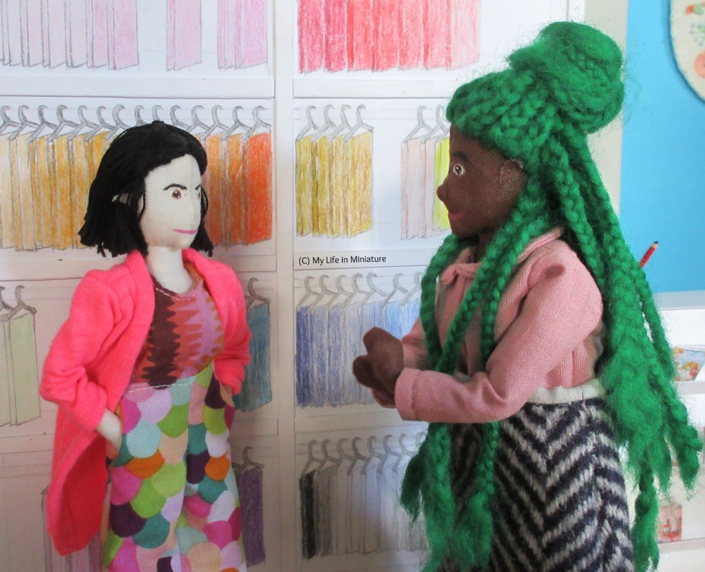 Hazel and Tiffany stand in Needle & Thread. Hazel has her hands clasped in front of her, clearly getting excited about her top. She grins at Tiffany, who has her hands in her pockets and is smiling back. 