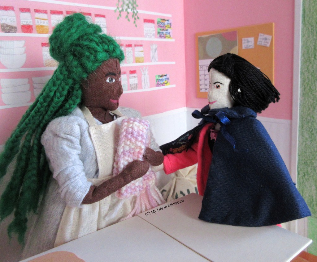 Hazel and Tiffany gather around a clean end of the Fierro's kitchen workbench. Hazel hugs her new scarf to her chest, smiling at Tiffany. Tiffany pats her elbow slightly awkwardly, smiling at Hazel. 