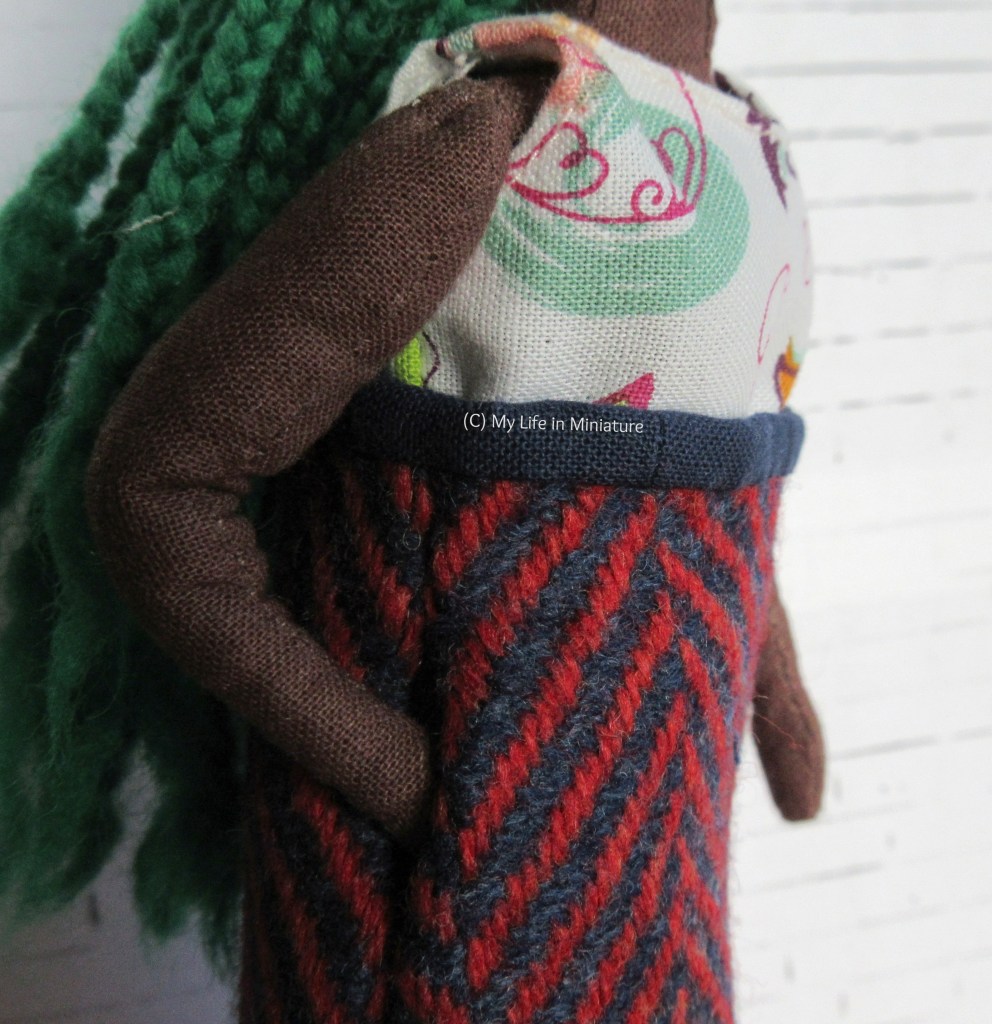 Close-up of the side of the skirt. Hazel's hand disappears into an in-seam pocket, and the slim navy waistband is visible. 