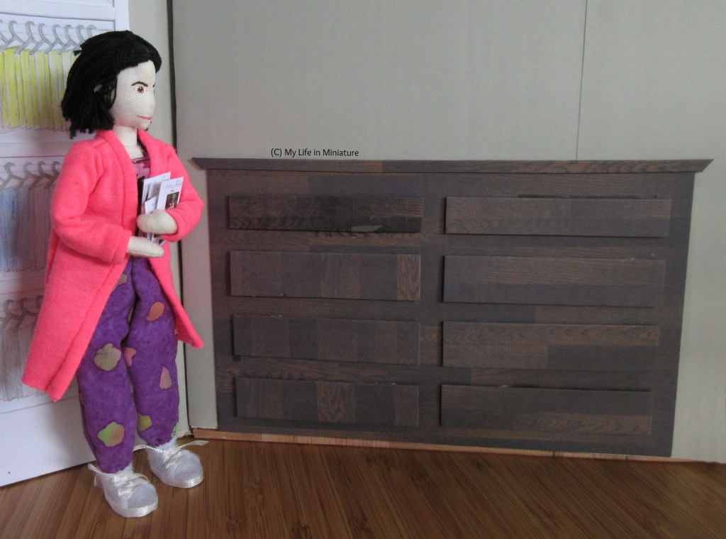 Tiffany smiles as she moves towards the chest of drawers against one wall of Needle & Thread. She has multiple sewing patterns in her arms, ready to sort them into the drawers.