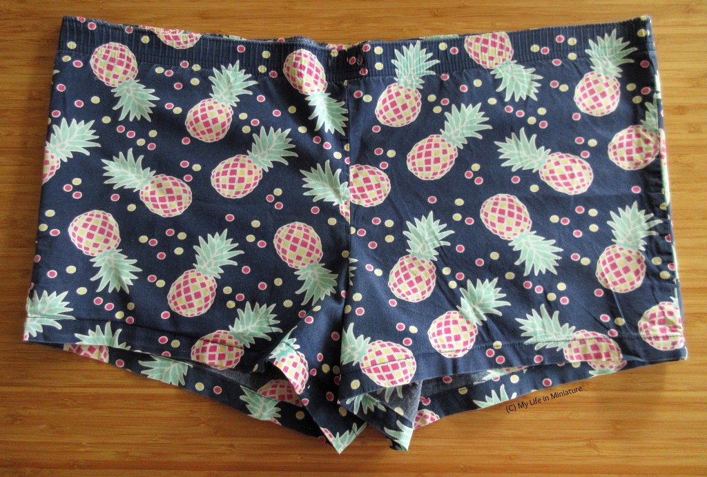 The same pyjama shorts, laid out flat on a wood surface, this time without the elastic waistband or the tie. 
