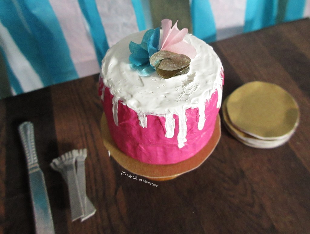 Close-up of the cake on the table. The paper flowers on top are clearer, as is the slightly lumpy icing job. 