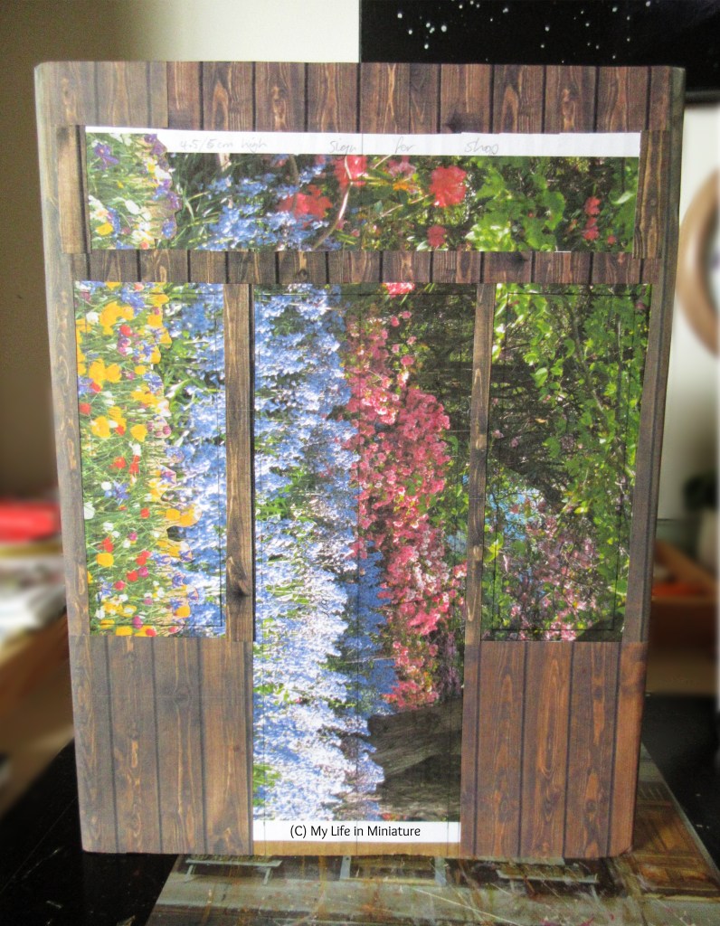 An unfinished storefront is photographed against a blurred background. The dark wood exterior outlines rectangles left open for the door, windows, and signage. 
