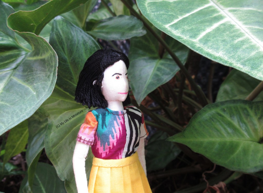 Tiffany stands beneath the canopy of leaves, looking up and to the right at them. 