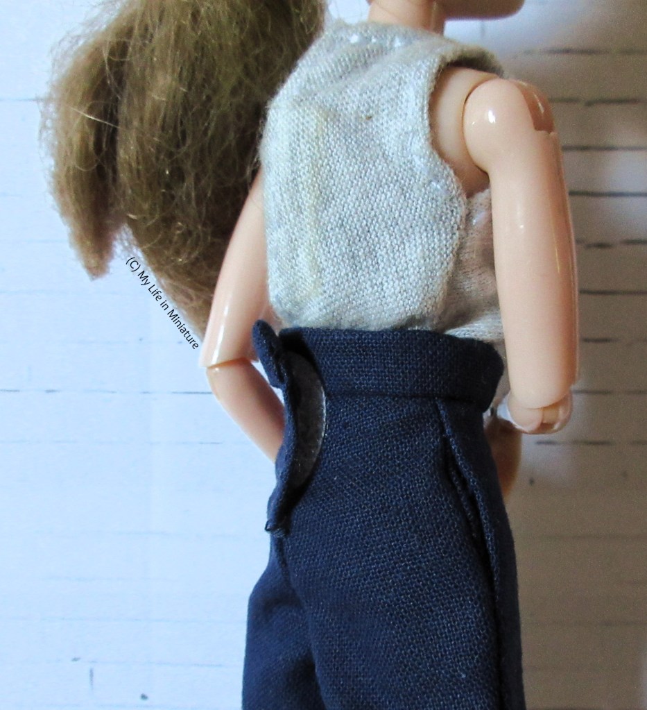 Close-up of the back and side of the navy pants. The Velcro closure in the back is visible, as well as the in-seam pocket's opening. 