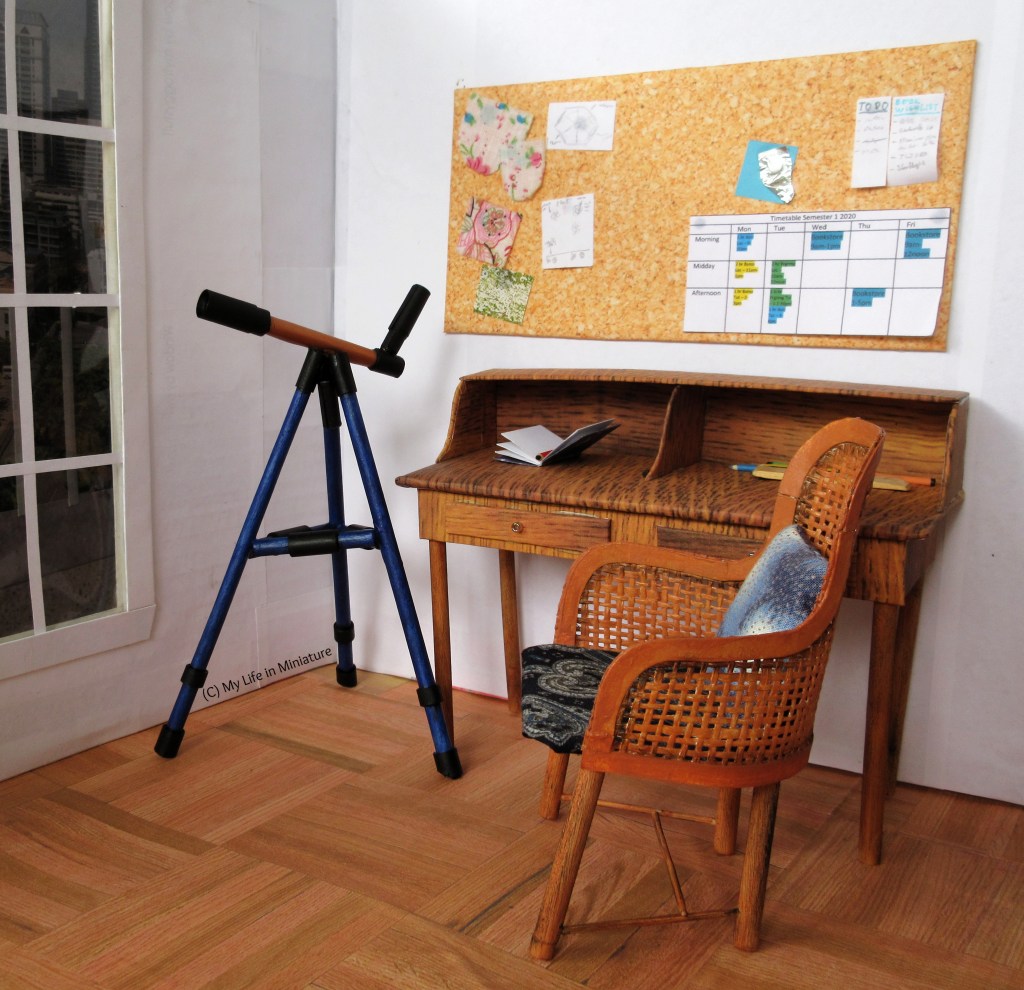 Sarah's telescope is in the corner of her bedroom next to her desk. The telescope looks much the same; fully assembled, same colours. The tripod has had a fresh paint job, and it looks generally less faded now. 