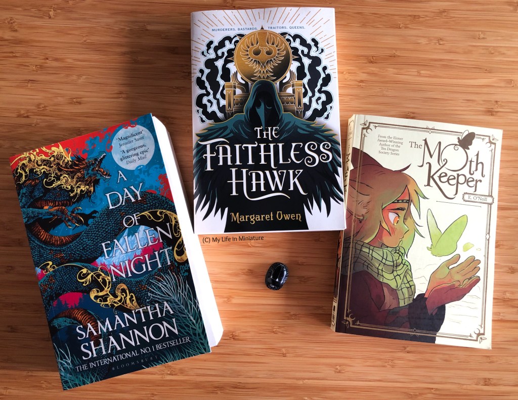 Three books are laid out next to each other, on a wood surface. 