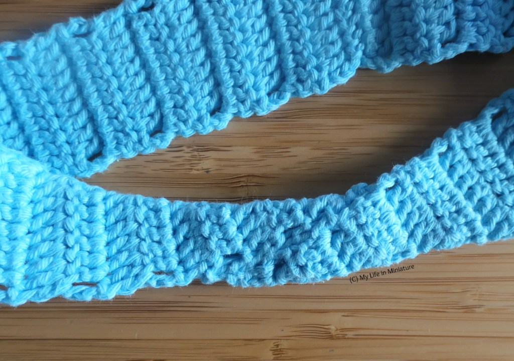 Close-up shot of the twist in the pale blue headband. The two opposite edges meet in a diagonal line at the twist, and are sewn together where they meet, 