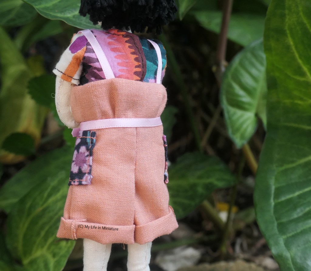 Close-up of the back of the dungarees. The back is lower than the front, and goes straight across from underarm to underarm.